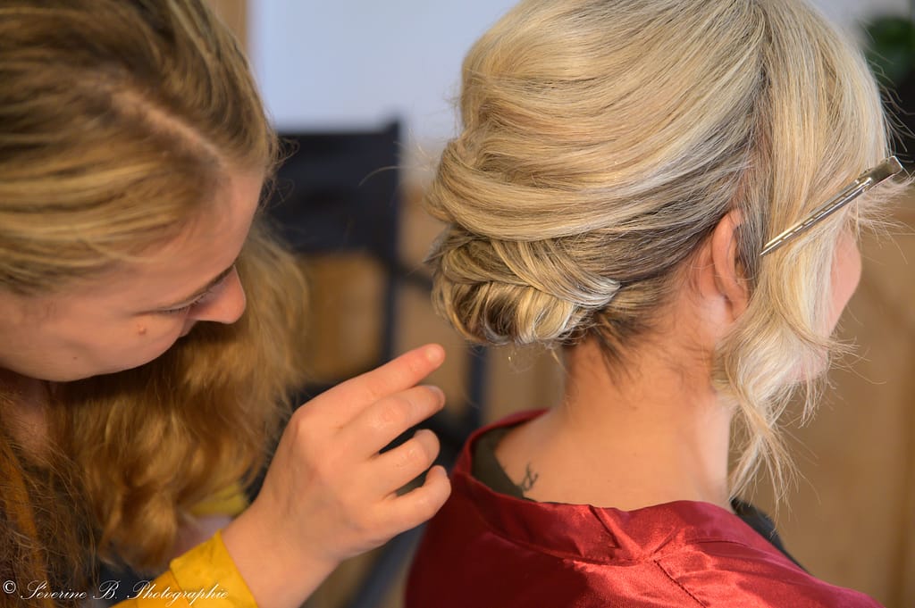 Mélanie Meyier, coiffeuse du duo Cannelles, travaille minutieusement sur le chignon blond de la mariée lors du Festival des 5 sens au Mas de la Baraque de Sérignac
