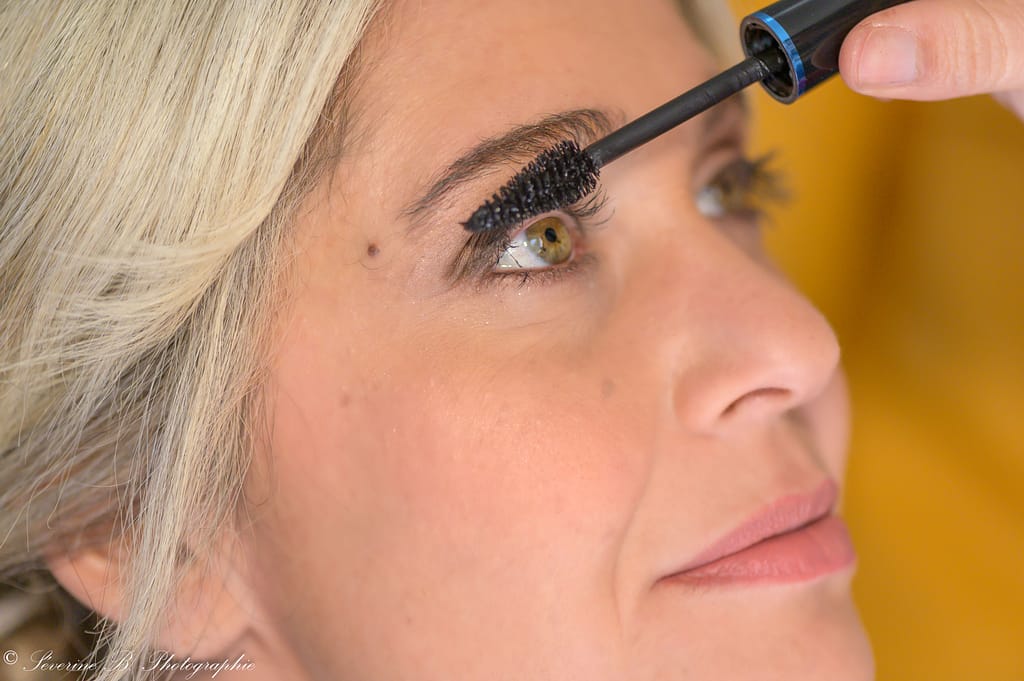 Gros plan macro sur l’œil mordoré‑vert de la mariée pendant l’application du mascara lors du Festival des 5 sens au Mas de la Baraque de Sérignac