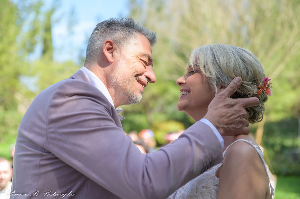 Les mariés de profil, le marié tenant la nuque de sa femme et s’apprêtant à l’embrasser, tandis qu’elle ferme les yeux, prête à recevoir le baiser