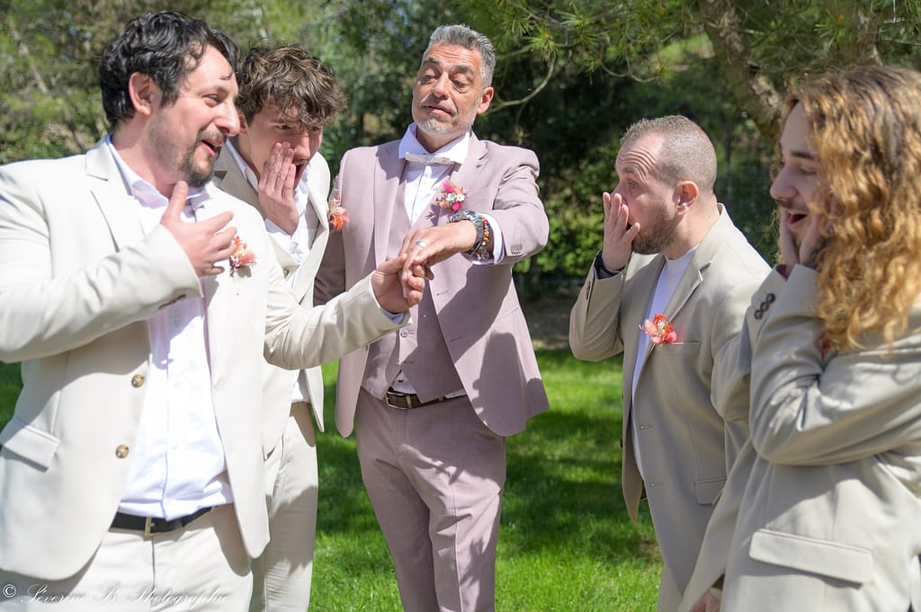 Le marié montre fièrement son alliance aux quatre garçons d’honneur qui réagissent avec des grimaces exagérées, comme des amies “trop choquées”, inversant avec humour les rôles hommes/femmes