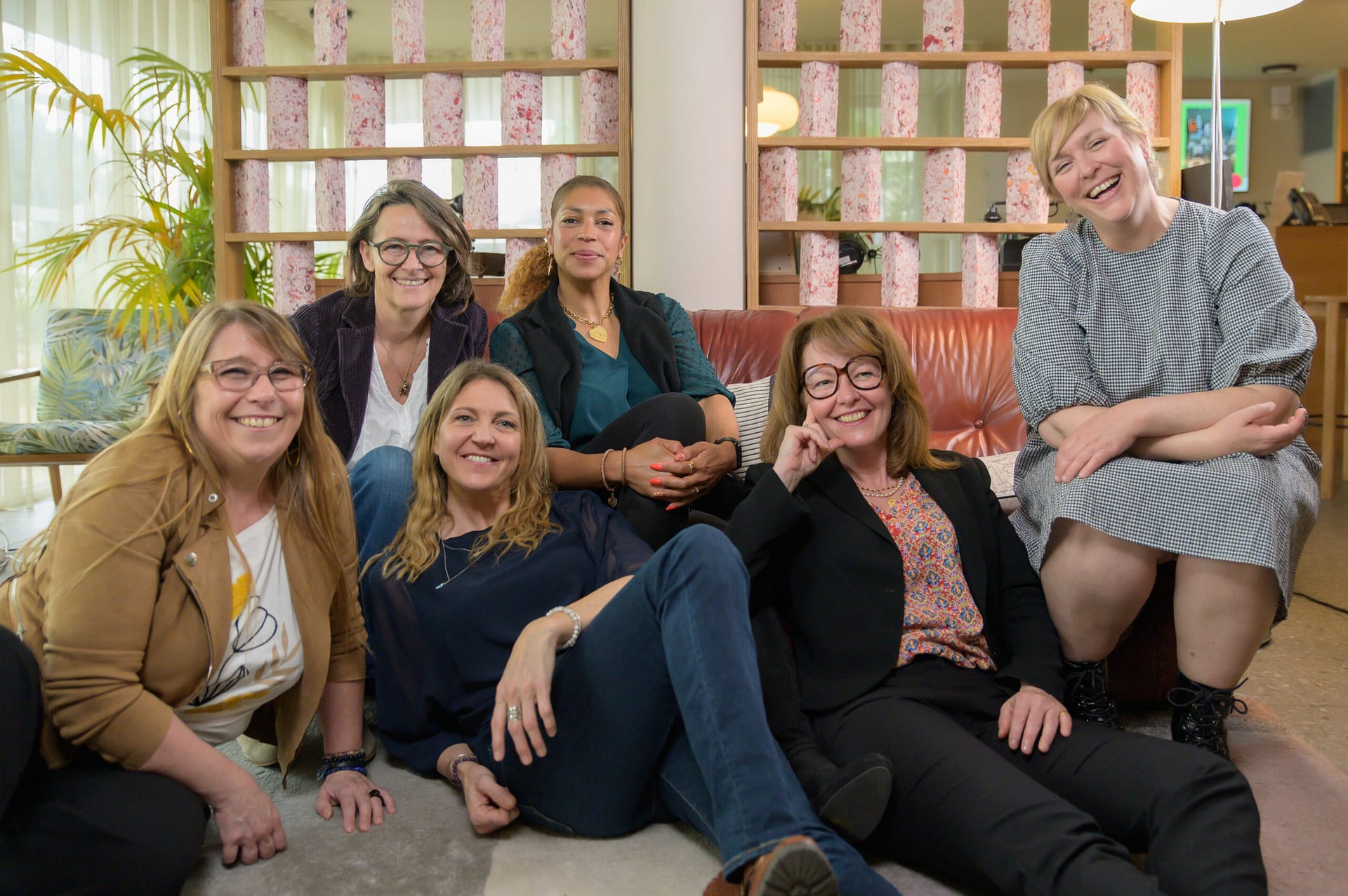 Six entrepreneuses sourient calmement ensemble lors du shooting professionnel au Greet Hôtel Montpellier, heureuses de se retrouver.