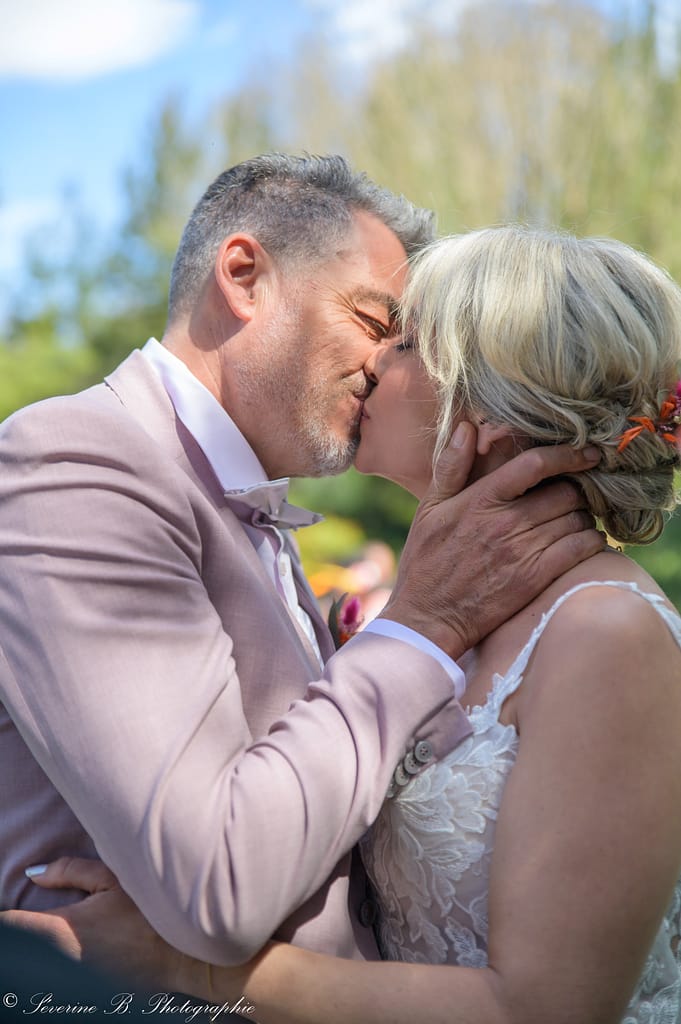 Les mariés s’embrassent, seuls au monde, leurs mains en contact sur le corps de l’autre dans une scène intense et romantique