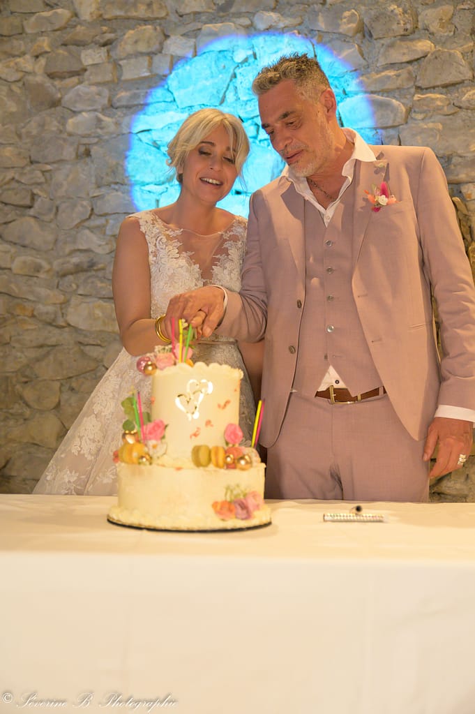 Les mariés découpent leur gâteau blanc, éclairés par un cercle de lumière bleue créé par le DJ